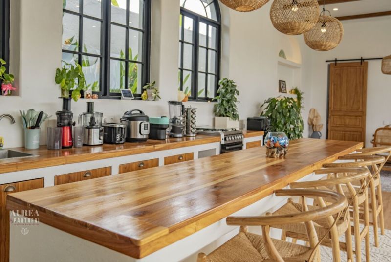 PREDAJ Unikátná 4KK Investičná zariadená vila s bazénom BALI-Jimbaran - Kuchyňa vily s elegantným dreveným pultom a okennými výhľadmi zelene.