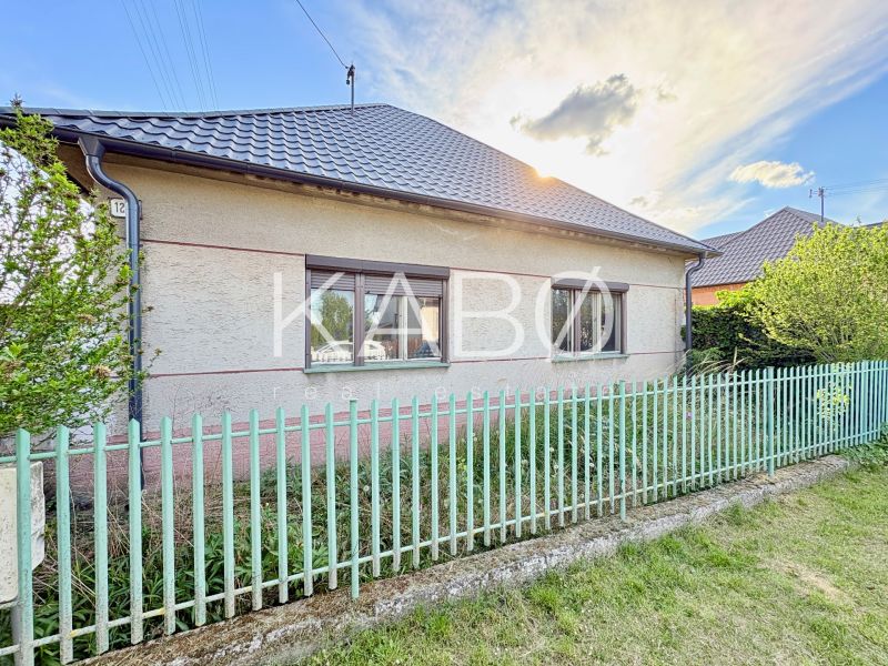 RD pripravený na rekonštruckiu - priestranný pozemok - tichá lokalita - Rodinný dom v Šoporni s dvoma oknami a kovovým plotom.