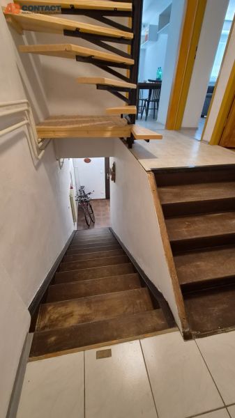 Tehlový 2-izbový byt s vlastným kúrením vo Vrbovom - Schodisko v 2-izbovom byte s dreveným dekorom a bicyklom pri vstupe.