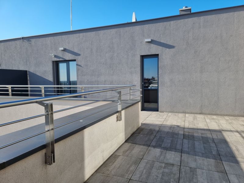 PRENÁJOM- Jedinečný, luxusný byt 148 m2 s terasami a parkovaním -Nitra - Na ulici Dolnohorská z 4-izbového bytu terasa s výhľadom, elegantné zábradlie, modrá obloha.
