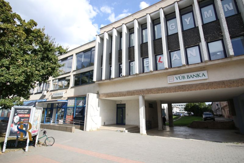 Prenájom centrum Galanty - Budova s kanceláriami a bankou v Galante, so stromom a chodníkom v popredí.