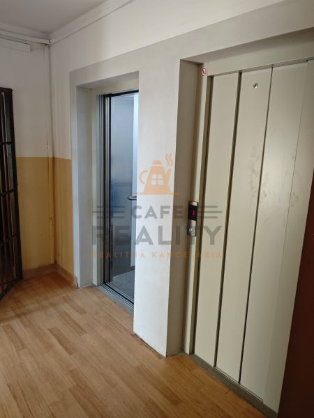 Na prenájom 1 izbový byt, 34 m2, Bratislava, Petržalka, Lachova ulica - Chodba s výťahom a podlahou s dreveným dekorom v 1-izbovom byte.