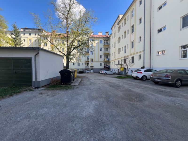 Na predaj priestranný 4-izbový byt - Robotnícka ulica, Banská Bystrica - Parkovisko pri bytovom dome v Banskej Bystrici s autami a stromami.