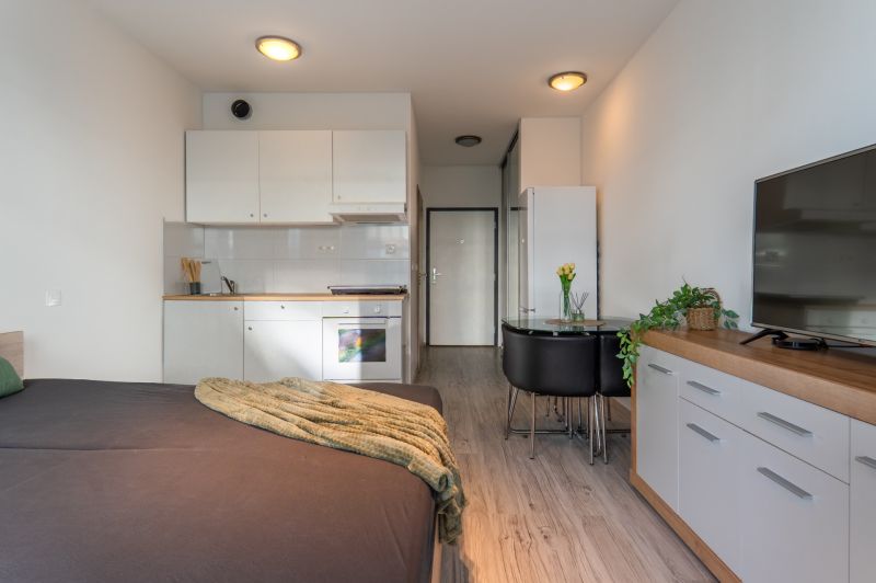 I Slnečnice – Zóna mesto moderný 1-izb byt s loggiou - 1-izbový byt s kuchyňou, jedálenským stolom a podlahou s dreveným dekorom.