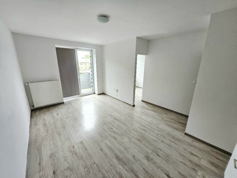 PRENÁJOM 1 IZBOVÝ BYT /34 M2/ SEVER / BALKÓN/ PIVNICA - Obývacia izba s bielymi stenami a podlahou s dreveným dekorom v 1-izbovom byte.