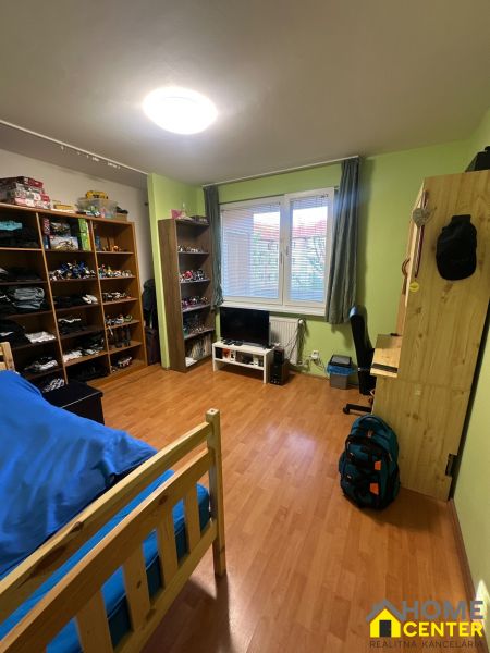 PREDAJ : 3 IZBOVÝ BYT S BALKÓNOM, KOMÁRNO  - Izba v 3-izbovom byte s policami, posteľou a podlahou s dreveným dekorom.