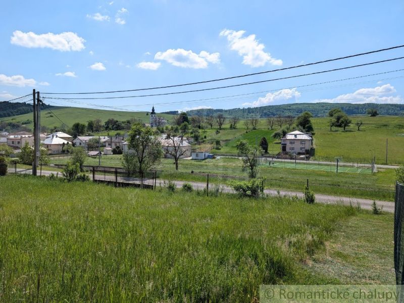 Slnečný stavebný pozemok 1 186 m² - Karná | možnosť dokúpiť 1 ha - Krajina v Karnej s výhľadom na kostol, domy a zeleň, Pozemky - bývanie.