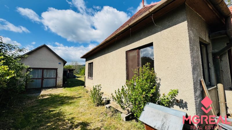 Na predaj 6-izbový rodinný dom (dvojdom) v Pažiti, pozemok 1445 m² - Rodinný dom v Pažiti so záhradou a samostatnou garážou pod modrou oblohou.