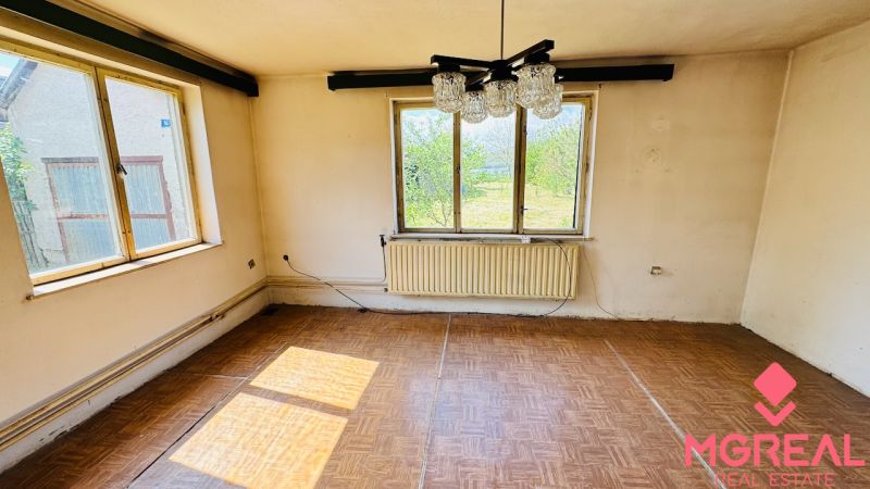 Na predaj 6-izbový rodinný dom (dvojdom) v Pažiti, pozemok 1445 m² - Izba v rodinnom dome s podlahou s dreveným dekorom a veľkými oknami.