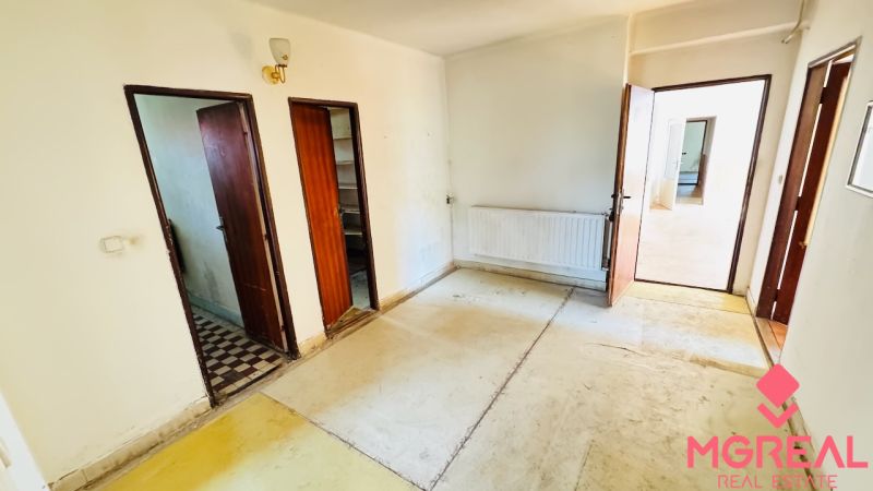 Na predaj 6-izbový rodinný dom (dvojdom) v Pažiti, pozemok 1445 m² - Interiér so starou podlahou, drevenými dverami a radiátorom v rodinnom dome.