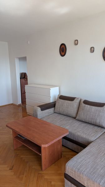 3 izbový byt v centre mesta na Štúrovej ulici s krásnym výhľadom - Obývacia izba so sedačkou, stolíkom a komodou, doplnená podlahou s dreveným dekorom.