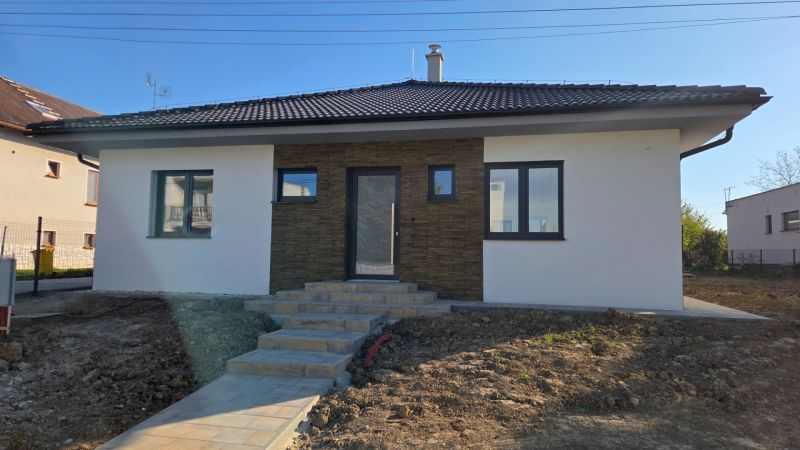 Bungalov v centre obce Cabaj Čápor, Wágnerova ulica, Dom č.1 - Rodinný dom v Cabaji-Čápore s bielou fasádou a kamenným obložením, svahovitý terén.
