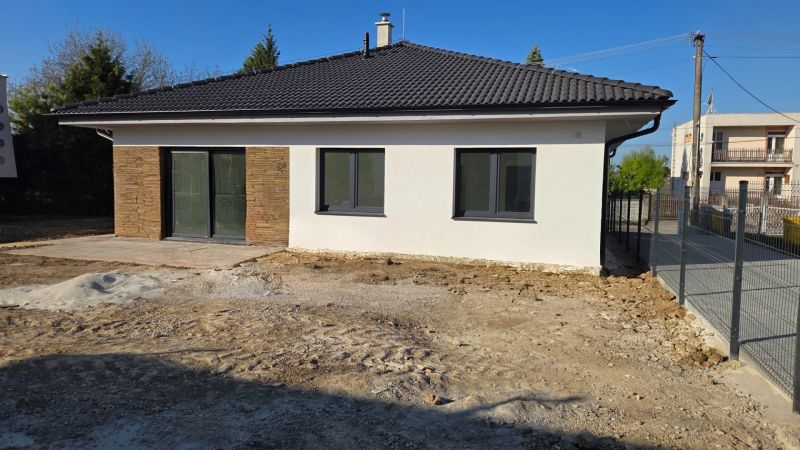 Bungalov v centre obce Cabaj Čápor, Wágnerova ulica, Dom č.1 - Rodinný dom v Cabaji-Čápore s bielou fasádou, kamennými detailmi a šikmou strechou.