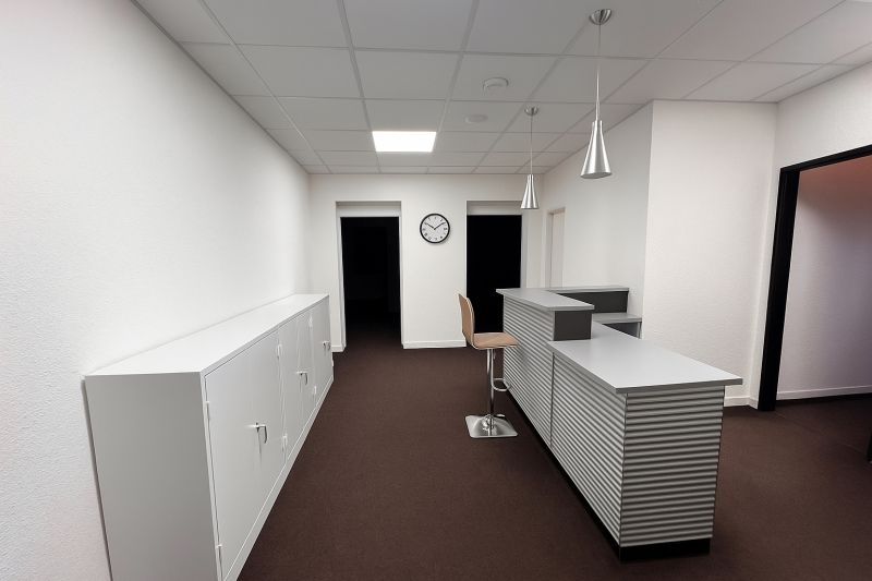 Prenájom Kancelárie 110 m² v centre Ružomberka - Kancelárie s recepciou, bielymi skrinkami a hnedým kobercom, podlaha s dreveným dekorom.