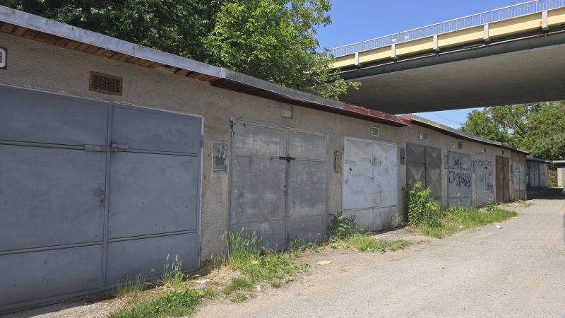 NA PREDAJ MUROVANÁ GARÁŽ 18 m² VO ZVOLENE – ELEKTRINA, VLASTNÝ POZEMOK - Garáže na Jesenského ulici v Zvolene popri ceste so zeleňou a grafitmi.