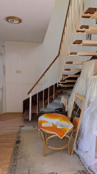 Radový domček na Zobore s výhľadom na mesto, Ružová ulica, garáž - Interiér rodinného domu so schodiskom, kreslom, stolom a podlahou s dreveným dekorom.