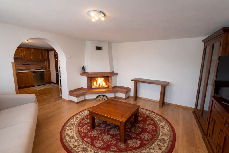 Rodinný dom Bacúch – rekonštrukcia. - Obývačka v rodinnom dome s krbom, podlahou s dreveným dekorom a oblúkovým prechodom.