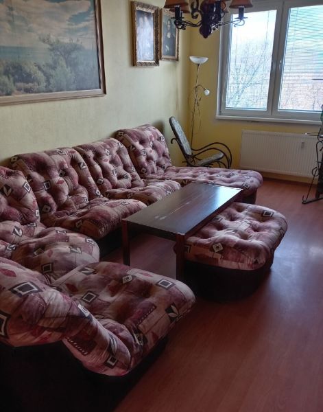 3,5 izbový byt na Klokočine, Partizánska ulica - Obývačka v 3-izbovom byte s pohovkou a kreslom, podlaha s dreveným dekorom.