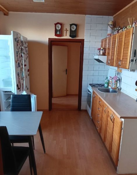 3,5 izbový byt na Klokočine, Partizánska ulica - Kuchyňa v 3-izbovom byte s podlahou s dreveným dekorom a nástennými hodinami.