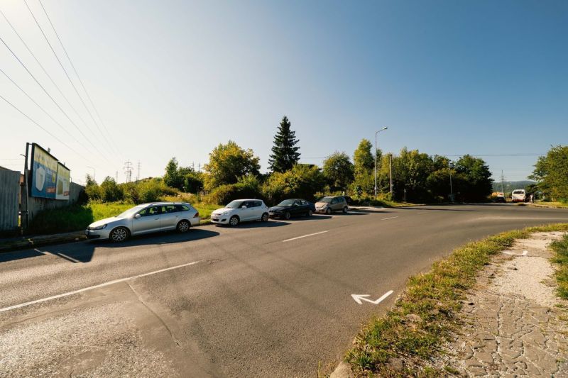 Na predaj stavebný pozemok pre rodinné domy – Banská Bystrica P306ZL - Cesta s parkujúcimi autami a billboardom na Partizánskej ceste, Banská Bystrica, Pozemky - bývanie.