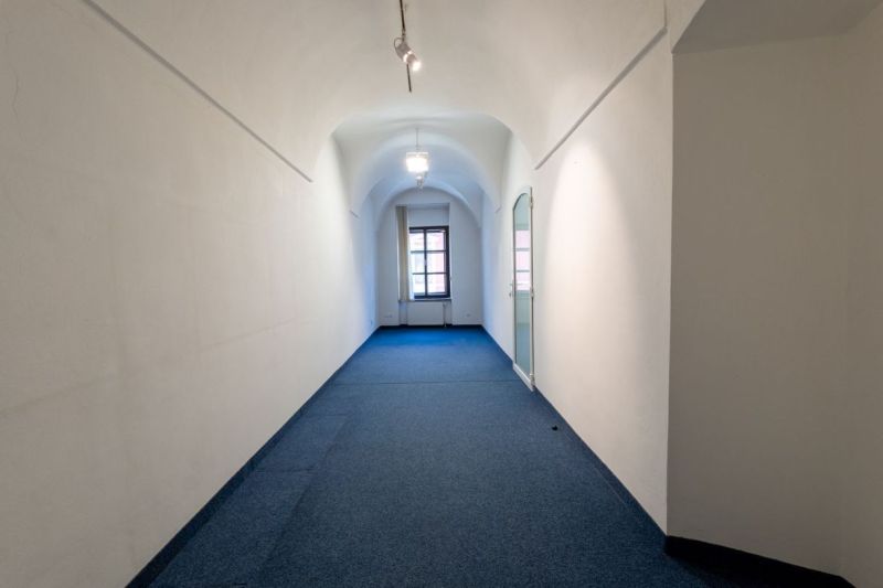 Reprezentatívny meštiansky dom s parkovaním v centre Banskej Bystrice  - Úzka chodba so zakriveným stropom, kobercom a veľkým oknom na konci.