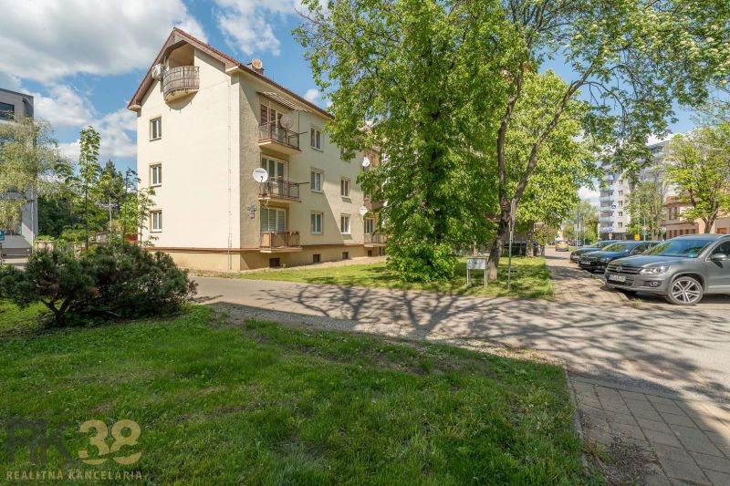 Exkluzívny 3-izbový podkrovný byt s krbom a balkónom - Exteriér budovy s 3-izbovým bytom v Poprade, obklopený zeleňou a parkoviskom.