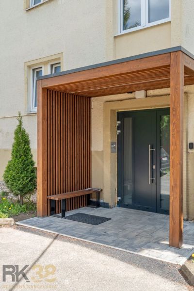 Exkluzívny 3-izbový podkrovný byt s krbom a balkónom - Vstup do bytového domu v Poprade s dreveným prístreškom a lavičkou.