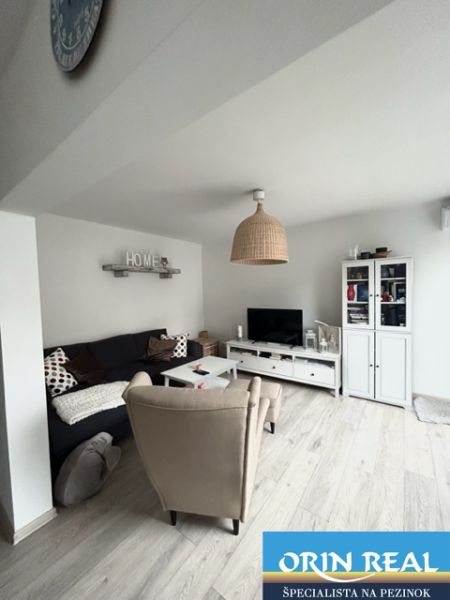 NA PRENÁJOM Pekný 2 izbový byt v Centre Pezinka 700,- EUR - Obývacia izba v 2-izbovom byte s podlahou s dreveným dekorom a pohodlným nábytkom.