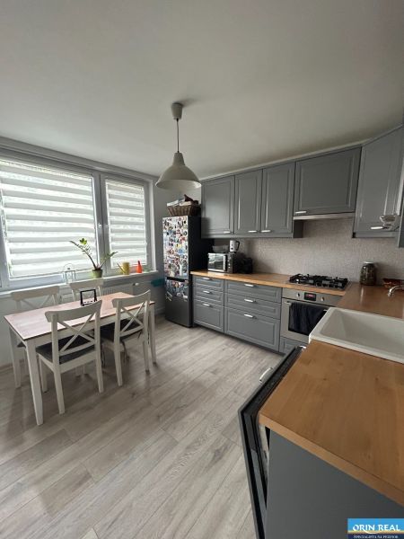 NA PRENÁJOM Pekný 2 izbový byt v Centre Pezinka 700,- EUR - Kuchyňa v 2-izbovom byte so sivými skrinkami a podlahou s dreveným dekorom.