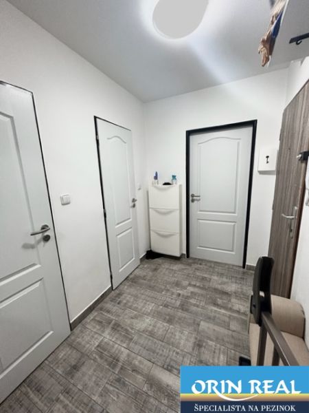 NA PRENÁJOM Pekný 2 izbový byt v Centre Pezinka 700,- EUR - Vstupná chodba v 2-izbovom byte s podlahou s dreveným dekorom a bielymi dverami.