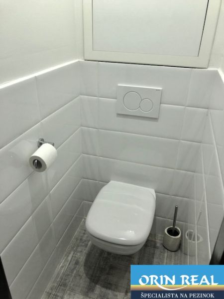NA PRENÁJOM Pekný 2 izbový byt v Centre Pezinka 700,- EUR - Toaleta s bielymi dlaždicami a podlahou s dreveným dekorom v 2-izbovom byte.
