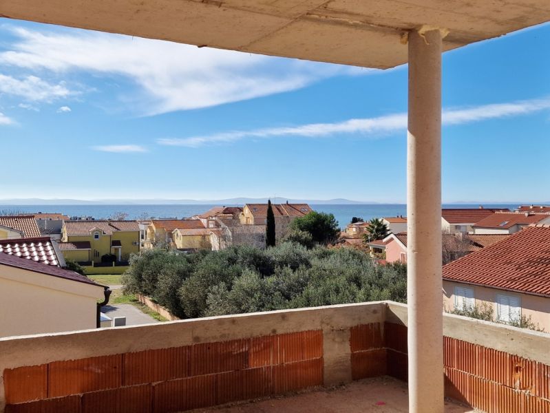 CHORVÁTSKO - 3 izbové apartmány PRIVLAKA, ZADAR - Výhľad na more z 3-izbového bytu v meste Privlaka, nad okolitými domami a stromami.