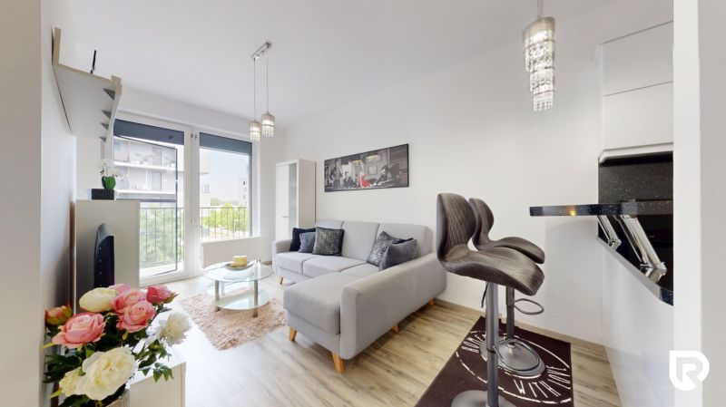 | Zariadený 1,5 izbový byt | 35m² | SLNEČNICE - Svetlý 2-izbový byt s pohovkou, barovými stoličkami a výhľadom cez veľké okno.