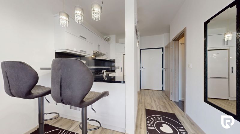 | Zariadený 1,5 izbový byt | 35m² | SLNEČNICE - Kuchyňa v 2-izbovom byte s barovými stoličkami a zrkadlom na stene.