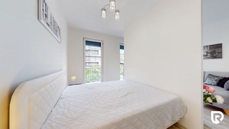 | Zariadený 1,5 izbový byt | 35m² | SLNEČNICE - Spálňa v 2-izbovom byte s pohodlnou posteľou a výhľadom na budovy.