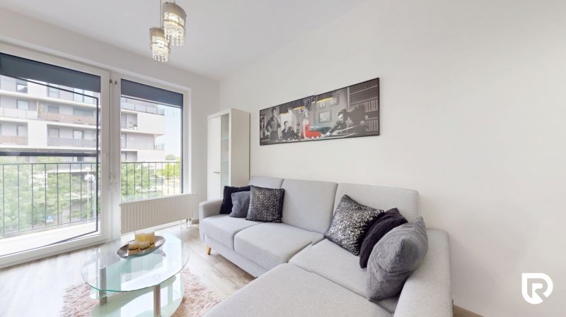 | Zariadený 1,5 izbový byt | 35m² | SLNEČNICE - Obývačka v 2-izbovom byte s pohodlnou sedačkou, obrazom na stene a veľkými oknami.