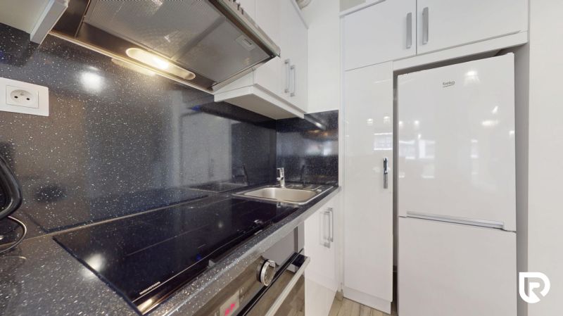 | Zariadený 1,5 izbový byt | 35m² | SLNEČNICE - Kuchyňa v 2-izbovom byte so vstavanými spotrebičmi, nerezovým drezom a lesklými skrinkami.