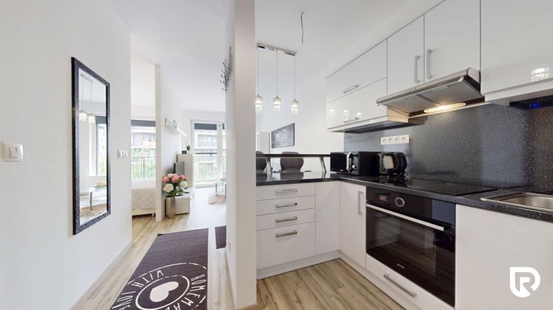| Zariadený 1,5 izbový byt | 35m² | SLNEČNICE - Kuchyňa v 2-izbovom byte s bielym nábytkom a dekoráciami.
