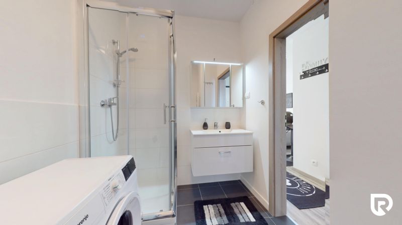 | Zariadený 1,5 izbový byt | 35m² | SLNEČNICE - Kúpeľňa v 2-izbovom byte, s práčkou, sprchovým kútom a umývadlom s osvetleným zrkadlom.