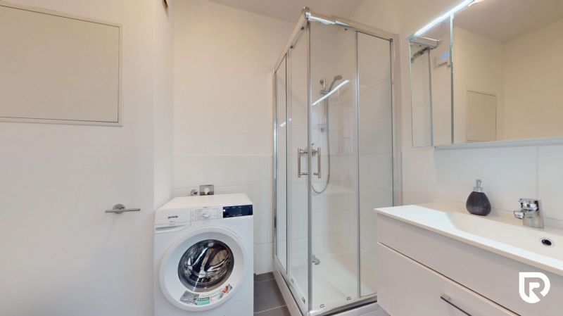 | Zariadený 1,5 izbový byt | 35m² | SLNEČNICE - Kúpeľňa v 2-izbovom byte so sprchovacím kútom, práčkou a umývadlom s úložným priestorom.