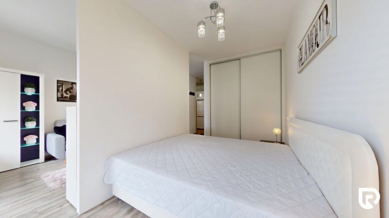 | Zariadený 1,5 izbový byt | 35m² | SLNEČNICE - Spálňa v 2-izbovom byte s bielou posteľou, vstavanou skriňou a dekoratívnymi prvkami.