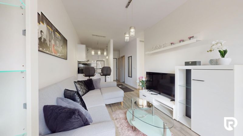| Zariadený 1,5 izbový byt | 35m² | SLNEČNICE - Štýlový obývací priestor v 2-izbovom byte s pohovkou a televíziou.