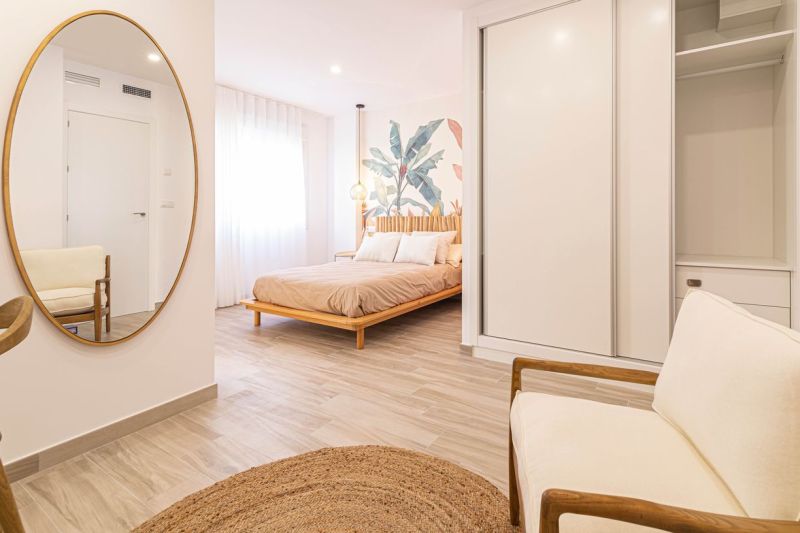 Predaj- Apartmány - La Manga del Mar Menor- Španielsko  - Interiér Rekreačného apartmánu s posteľou, zrkadlom a podlahou s dreveným dekorom.