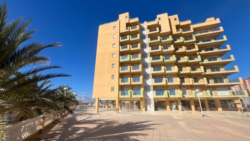 Predaj- Apartmány - La Manga del Mar Menor- Španielsko  - Rekreačný apartmán v La Manga del Mar Menor s palmami a jasnou oblohou.