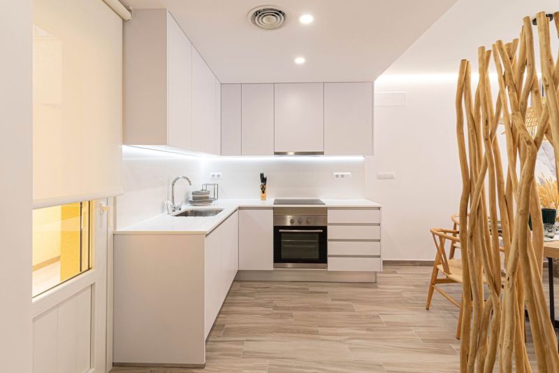 Predaj- Apartmány - La Manga del Mar Menor- Španielsko  - Kuchyňa v rekreačnom apartmáne s bielymi skrinkami a podlahou s dreveným dekorom.