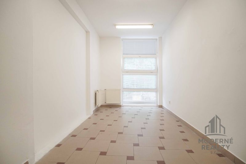 Na prenájom kancelária v centre mesta na ul. M. R. Štefánika, Nové Zám - Interiér kancelárie s oknom a radiátorom, podlaha s dlažbou.