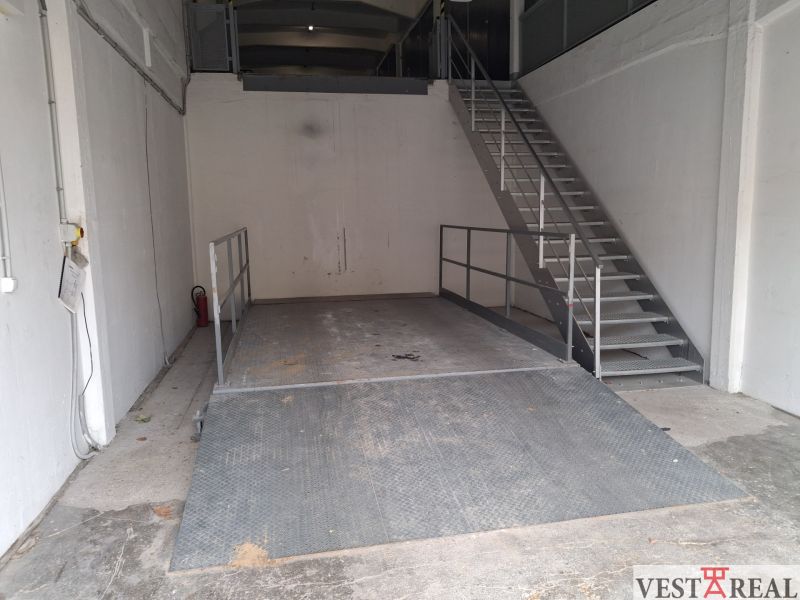 Na prenájom skladové priestory od 25 m2 Trnava Coburgova - Sklady a haly s kovovou plošinou a schodiskom, biele steny, industriálny vzhľad.