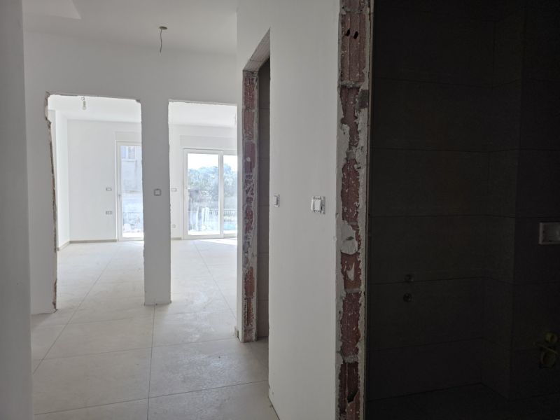 CHORVÁTSKO - Apartmány 140 m od pláže (3i) - VODICE - Interiér 3-izbového bytu s bielymi stenami a balkónovými dverami a svetlou podlahou.