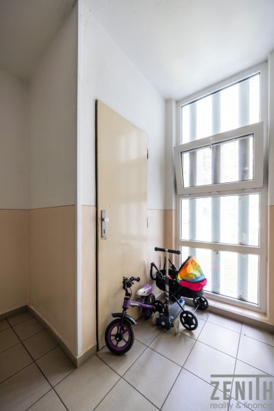 Štýlový 3-izbový byt po kompletnej rekonštrukcii – stačí sa nasťahovať - Chodba s detským bicyklom pri okne a dverách v 3-izbovom byte.