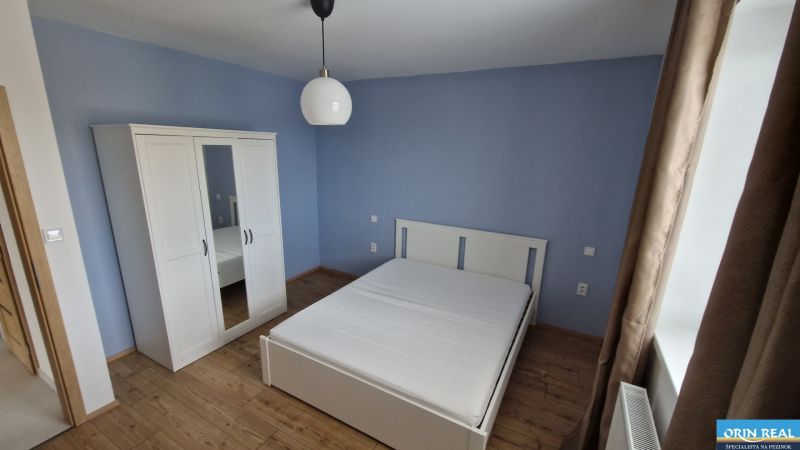 NOVÝ ZARIADENÝ BYT NA Muškáte - Spálňa v 2-izbovom byte s posteľou, šatníkom a drevenou podlahou.